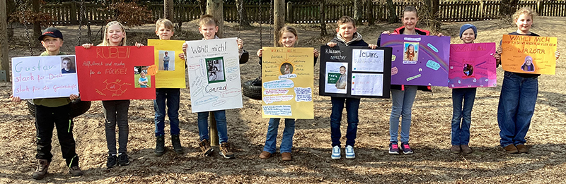 Die Kinder der 3. Klasse präsentieren stolz ihre Wahlplakate
